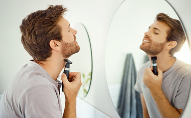 Image showing Mirror reflection, grooming and man shaving in the bathroom of a home in the morning for personal hygiene. Electric razor, skincare and routine with a young male person in his house for hair removal