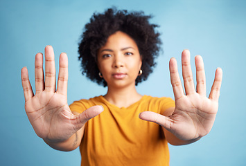 Image showing Portrait, stop hands and serious woman in studio isolated on a blue background. African person, face and ban, rejection or warning, refuse and no palm sign to protest racism, human rights and emoji.