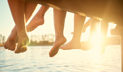 Image showing Group, feet on water and friends together at ocean, pier or outdoor in summer, vacation or freedom in holiday break. Teen, foot and children to relax at the lake, harbor or river on the weekend