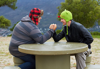 Image showing Arm wrestling, happy friends and outdoor at table for sports, challenge and exercise. Strong, conflict and men holding hands for competition, power and muscle match, training or workout in park.