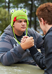 Image showing Arm wrestling, friends and outdoor at table for sports, challenge and exercise. Strong, conflict and men holding hands for competition, serious power and muscle match, training or workout in park.