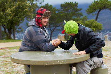 Image showing Arm wrestling, friends and winning outdoor at table for sports, challenge and exercise. Strong, conflict and men holding hands for competition, power and muscle match, training or workout in park.