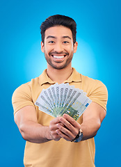 Image showing Money, portrait and man or winner with bonus offer, financial success and winning, finance loan or lottery fan. Young asian person with savings, cash and profit isolated on studio, blue background