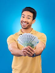 Image showing Cash, portrait and happy man or winner for bonus offer, financial success and winning, finance loan or lottery fan. Young asian person with savings, money or profit isolated on studio blue background