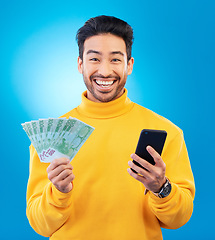 Image showing Success, money and portrait of Asian man with phone in studio for online bonus, competition and lottery. Winner, finance and male person on blue background with cash for promotion, winning and deal