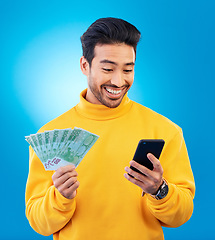 Image showing Man, phone and money in studio with prize, esports gambling or happy for success by blue background. Young asian guy, student and smartphone with cash, fintech or crypto with profit, bonus or goals