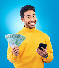 Image showing Cash, money and portrait of Asian man with phone in studio for online bonus, competition and lottery. Success, finance and male person on blue background excited for promotion, winning and deal