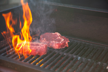 Image showing Beef steaks on the grill with flames