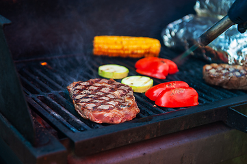 Image showing Beef steaks on the grill with flames