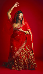 Image showing Fashion, dancing and Indian woman in a traditional dress, celebration and confident on a red studio background. Female person, girl and model with a cultural outfit, dancer and ritual with confidence