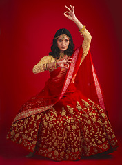 Image showing Portrait, dance and Indian woman with fashion, traditional dress and celebration against a red studio background. Face, female person or model with cultural clothes, jewellery and dancing with beauty