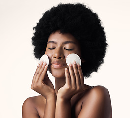 Image showing African woman, skincare and cotton pad in studio with afro, face and cosmetics with product by background. Girl, model and happy for natural self care with makeup, eyes closed and cleaning for beauty