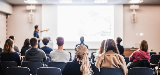 Image showing Speaker giving a talk in conference hall at business event. Rear view of unrecognizable people in audience at the conference hall. Business and entrepreneurship concept.