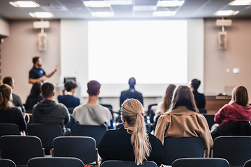 Image showing Speaker giving a talk in conference hall at business event. Rear view of unrecognizable people in audience at the conference hall. Business and entrepreneurship concept.