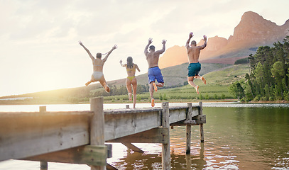 Image showing Lake, jump and group of friends for holiday, summer camping and freedom, celebration or success from behind. carefree, cheers and excited people in air for swimming, water and mountains on vacation