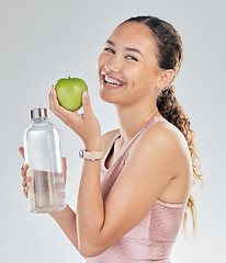 Image showing Portrait, woman and water bottle with apple in studio for diet of healthy food, nutrition and detox for weightloss. Happy female fitness model, hydration and fruit to lose weight on white background