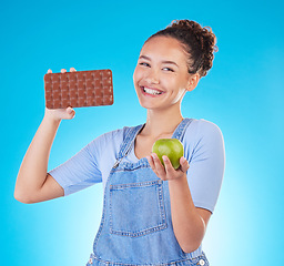 Image showing Apple, chocolate and woman for healthy food choice or offer isolated on studio, blue background for food, sugar and diet. Dessert, green fruit and happy young person for detox or lose weight decision