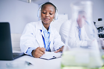 Image showing Research notes, music and a black woman in a lab studying healthcare and writing a report. Innovation, education and an African scientist with headphones for a podcast while doing medical paperwork