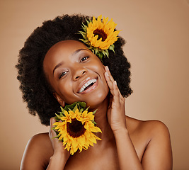 Image showing Portrait, skincare and sunflower with a model black woman in studio on a brown background for cosmetics. Face, beauty or natural and a happy young female person with a flower in her afro hair