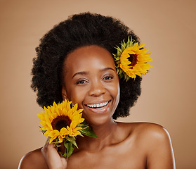 Image showing Portrait, beauty and sunflower with a model black woman in studio on a brown background for cosmetics. Face, skincare or natural and a happy young female person with a flower in her afro haira