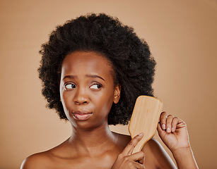 Image showing Sad black woman, hair and unhappy with brush in studio, brown background and afro. Beauty, worried african female model and comb hairstyle with anxiety, knot and problem of damage to natural texture