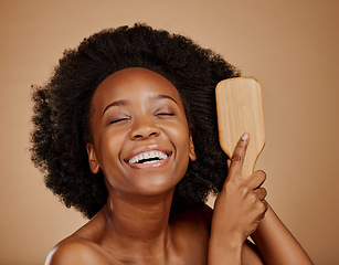 Image showing Happy black woman, brush and hair care in studio, brown background and treatment of curly texture. Natural beauty, smile and face of young african female model comb clean, healthy or afro hairstyle