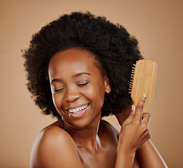 Image showing Happy black woman, afro and brush hair in studio, brown background and treatment of curly texture. Natural beauty, smile and face of young african female model with comb, hairstyle or aesthetic tools