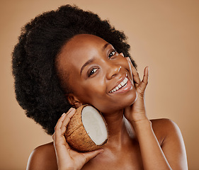 Image showing Portrait, skincare and coconut with a model black woman in studio on a brown background for natural treatment. Beauty, skin and cosmetics with a happy young female person holding fruit for oil