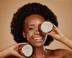 Image showing Portrait, beauty and coconut with a model black woman in studio on a brown background for natural treatment. Smile, skincare and cosmetics with a happy young female person holding fruit for oil