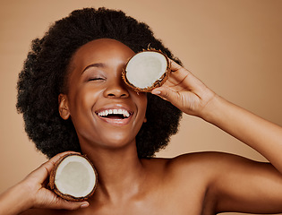 Image showing Happy, glow and black woman with coconut for skincare, dermatology treatment and health. Laughing, wellness and an African model with a smile for food for hair care isolated on a studio background