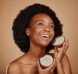 Image showing Beauty, skincare and coconut with a model black woman in studio on a brown background for natural treatment. Thinking, skin and cosmetics with a happy young female person holding fruit for oil