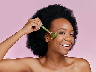 Image showing Happy, skincare and portrait of black woman with a jade roller for a facial massage or treatment. Smile, relax and African girl or model with a facial product isolated on a pink background in studio