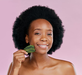 Image showing Gua sha, facial massage and black woman with natural beauty, face care and skin glow on pink background. Female model, jade cosmetic tools and dermatology with afro hair and skincare in studio