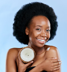 Image showing Portrait, body and coconut with a model black woman in studio on a blue background for natural treatment. Beauty, skincare and smile with a happy young female person holding fruit for cosmetic oil