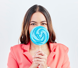 Image showing Portrait, lollipop and woman with sweets, sugar and confident girl on a white studio background. Face, female person or model with candy, dessert and cover with treats, cheerful and confectionary