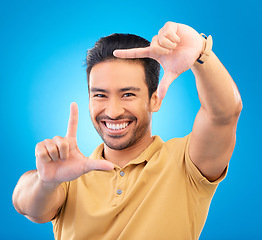 Image showing Portrait, finger frame and man in studio, blue background and review profile picture. Face, happy asian model and hands for planning perspective of photography, selfie and inspiration of photographer