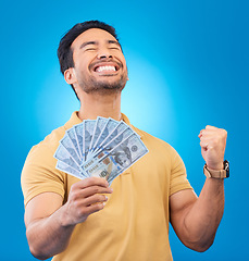 Image showing Money, studio and man excited, cheers and smile for dollar bills, financial achievement award or bonus prize. Cash, competition winner and person happy for income, revenue or pay on blue background