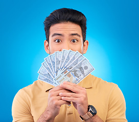 Image showing Money, shocked face and man with financial surprise, winning or savings mistake isolated on blue, studio background. Lottery, finance secret and asian person gambling, bonus and cashback in portrait