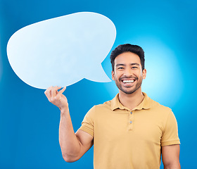 Image showing Man, speech bubble and studio portrait with smile for opinion, social media and poster by blue background. Indian guy, student or model with billboard, mockup space and cardboard sign for promotion