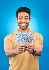 Image showing Happy, portrait of a man with money fan and in a blue background for financial freedom. Rich or cash, investment or budget and male person pose for economy growth or winner in a studio backdrop