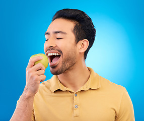 Image showing Hand, man eating an apple and against a blue background for healthy diet. Nutrition or mockup space, isolated or green food and male person eat fruit for health wellness against a studio backdrop