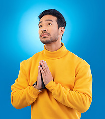 Image showing Peace, man with hand gesture and praying against a blue background for worship. Thank you or faith, spiritual growth or meditation and young male person with emoji hands sign for religion in studio