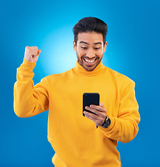 Image showing Winner, surprise and excited Asian man with phone in studio for online bonus, competition and prize. Success, smartphone and happy male person on blue background for promotion, winning and good news