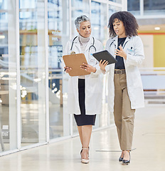 Image showing Collaboration, tablet and documents with woman doctors walking in a hospital for healthcare or medical discussion. Teamwork, medical and consulting with medicine professionals talking in a clinic