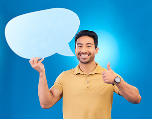 Image showing Young man, speech bubble and studio portrait for thumbs up, opinion and social network by blue background. Indian guy, student or model for yes icon, mock up space and cardboard sign for promotion