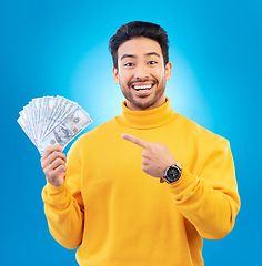 Image showing Money, studio portrait and happy man point at dollar bills, competition reward or bonus salary prize. Savings pay, cash winner and excited person show income, success or wealth on blue background