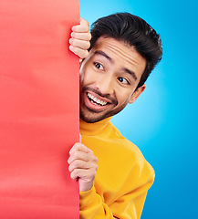 Image showing Shock, hide and young man with billboard with wow, omg or wtf facial expression in studio with mockup. Happy, surprise and male model with sneaky face by poster with mock up space by blue background.