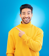 Image showing Man, point and smile in studio portrait with choice, fashion and promotion with excited face by blue background. Young Indian guy, gen z student and finger for decision, icon and opinion with clothes