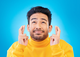 Image showing Hope, man with his fingers crossed for luck and against a blue background for thinking. Praying or miracle, trust and male person with hand emoji for aspiration or idea against a studio backdrop.