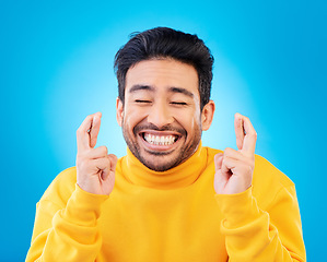 Image showing Hope, man with his fingers crossed for luck and against a blue background for competition. Praying or miracle, trust and male person with hand emoji for aspiration or wish against a backdrop.